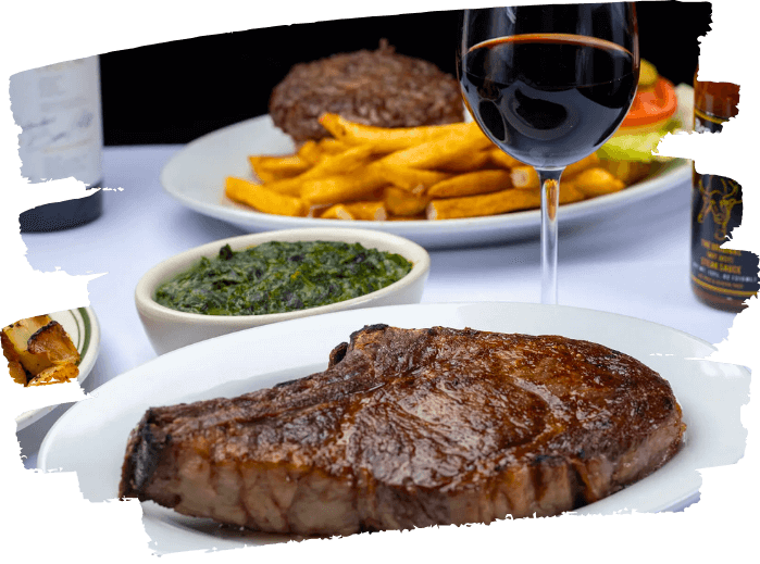 Grilled steak on a white plate with a side of creamed spinach, fries, and a glass of red wine.
